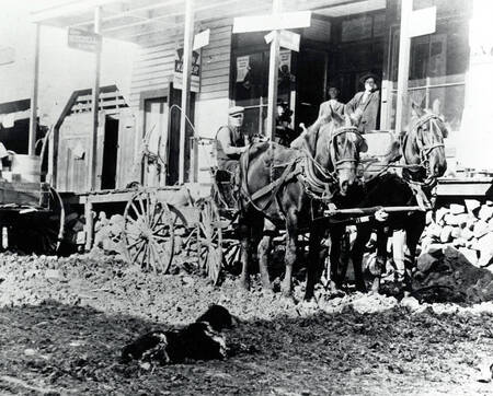 Wagon pulled by team and men on porch in front of Erb Brothers General Store.
