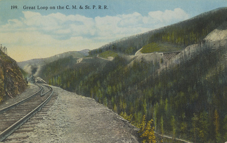 Postcard of railroad tracks in a mountain pass. Possibly the Chicago, Milwaukee, St. Paul and Pacific Railroad (often referred to as the Milwaukee Road) in Idaho.